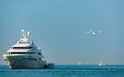 A private jet flying over a superyacht