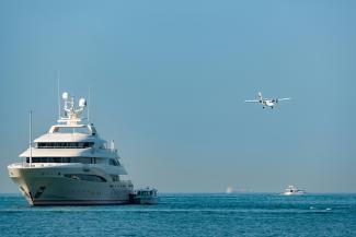 A private jet flying over a superyacht
